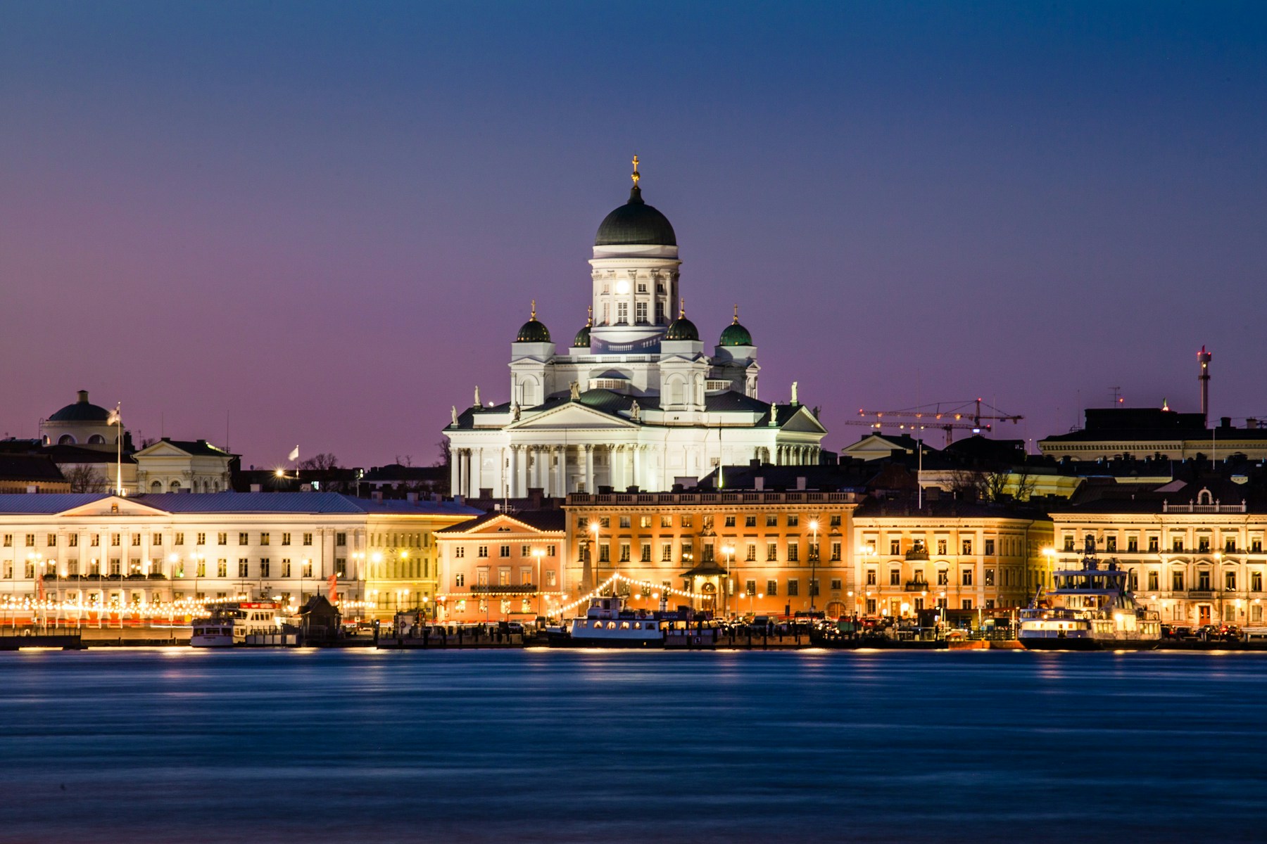 Helsingin tuomiokirkko ja valaistu Kauppatorin ranta iltahämärässä